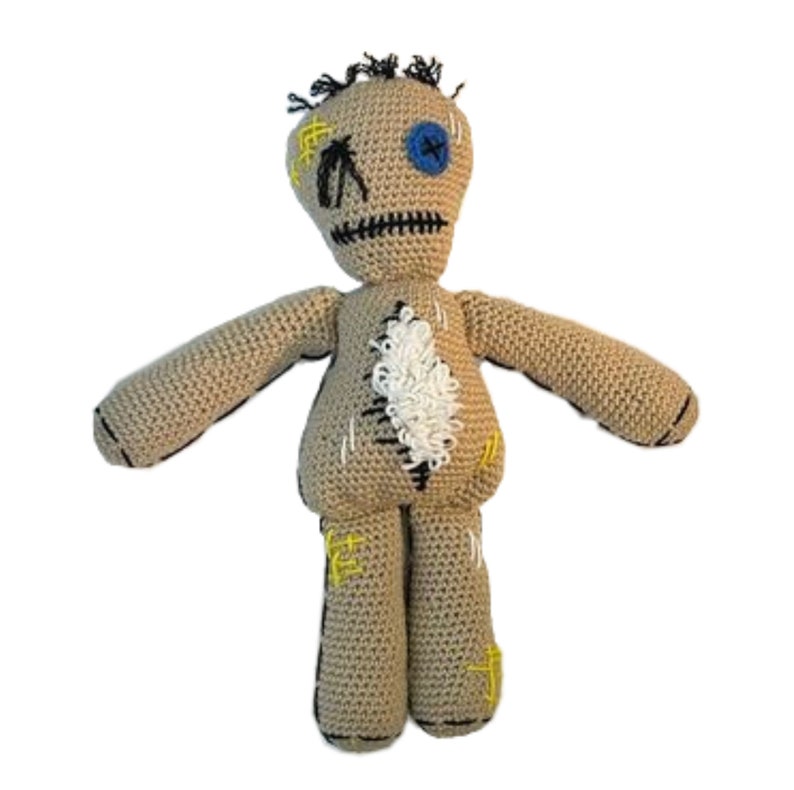 May include: A crocheted voodoo doll with a beige body, black hair, a blue button eye, and yellow and black stitching.
