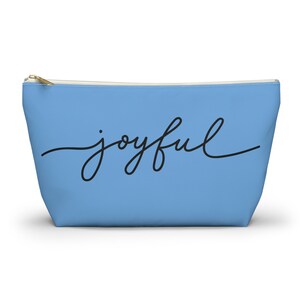 May include: A light blue zippered pouch with the word "joyful" written in black cursive script.