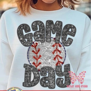 May include: White sweatshirt with a glittery black and silver design that says "Game Day" with a baseball in the middle.