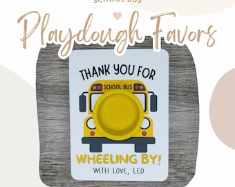 Può includere: Un biglietto bianco con un'illustrazione di autobus scolastico giallo e il testo "Grazie per essere passato! Con affetto, Leo". Il biglietto è attaccato a una superficie di legno. C'è la plastilina all'interno dell'autobus.