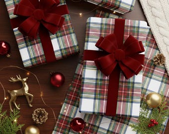 May include: Overhead shot of wrapped gifts with red velvet bows and plaid wrapping paper. The gifts are surrounded by Christmas ornaments, a gold reindeer figurine, and pine cones on a wooden surface. A white cable-knit blanket is in the background.