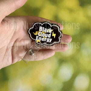 May include: A black cloud-shaped badge reel with the words "Black Cloud Energy" in white and yellow, with yellow lightning bolts. The badge reel has a clear plastic strap and a metal clip.