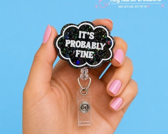 Può includere: Un porta badge a forma di nuvola nera con glitter multicolori e il testo bianco IT'S PROBABLY FINE. Il porta badge è dotato di un cinturino in plastica trasparente con un bottone a pressione in metallo e un meccanismo a cordino retrattile.