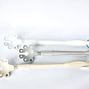 May include: Three plastic kitchen utensils with a flower-shaped head and a long handle. The utensils are white, gray, and beige.