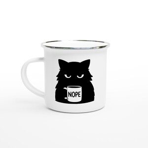 Könnte beinhalten: Eine weiße Keramik-Tasse mit schwarzem Henkel und dem Text "But First, Coffee" in fetter, schwarzer Schrift. Die Tasse steht vor einem neutralen Hintergrund, der ihr schlichtes Design hervorhebt.