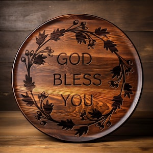 May include: A round wooden serving tray with a dark brown wood grain finish. The tray features a decorative design of a floral wreath with the words "God Bless You" engraved in the center.