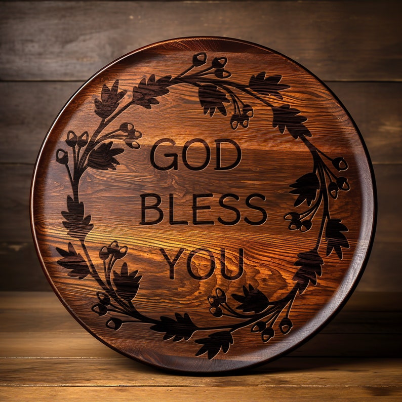 May include: A round wooden serving tray with a dark brown wood grain finish. The tray features a decorative design of a floral wreath with the words "God Bless You" engraved in the center.