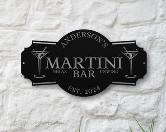May include: A black metal wall sign with a decorative scalloped edge featuring the text "ANDERSON'S MARTINI BAR", "RELAX UNWIND", and "EST. 2024". The design includes two martini glass illustrations, one on each side of the central text.