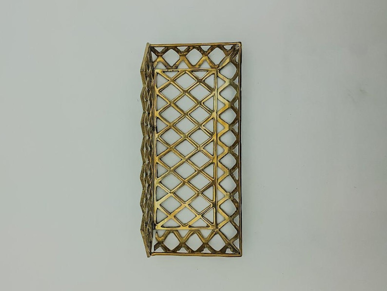 May include: A gold metal tray with a diamond-shaped wire mesh design. The tray is empty and has a rectangular shape.