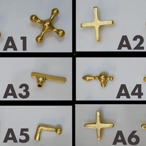 K&ouml;nnte beinhalten: Sechs verschiedene Stile von goldfarbenen Wasserhahngriffen, gekennzeichnet mit A1 bis A6. Die Griffe sind aus Metall und haben verschiedene Formen, darunter ein Stern, ein Kreuz und ein Hebel.