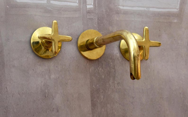 K&ouml;nnte beinhalten: Goldfarbener Badezimmerhahn mit zwei kreuzf&ouml;rmigen Griffen.