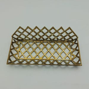 May include: A gold metal tray with a diamond pattern design. The tray is open and ready to hold items.