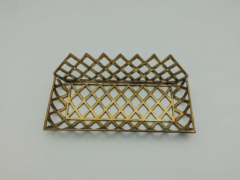 May include: A gold metal tray with a diamond pattern design. The tray is open and ready to hold items.
