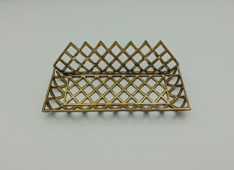 May include: A gold metal tray with a diamond-shaped grid pattern. The tray is rectangular and has a raised edge.