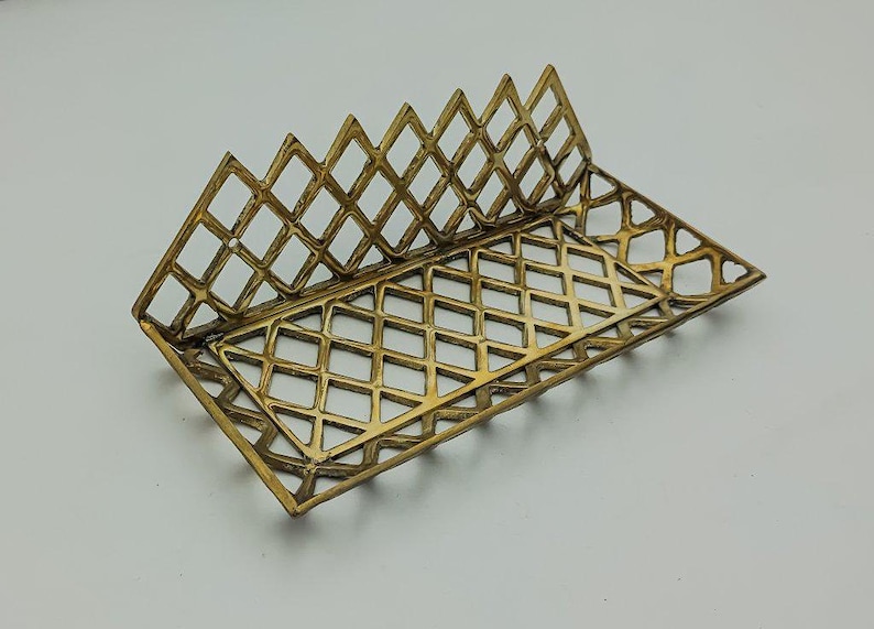 May include: A gold metal tray with a diamond pattern design. The tray is made of a thin metal and has a delicate, intricate design.