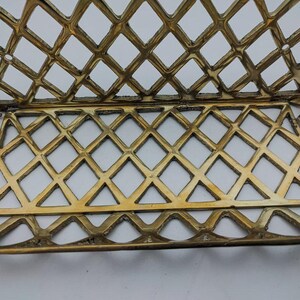May include: A gold-colored metal letter holder with a diamond-shaped grid pattern. The holder is designed to hold letters or other documents.