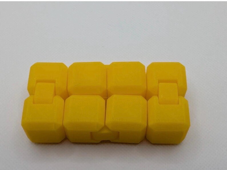 May include: A bright yellow fidget toy composed of eight connected, rectangular blocks. Each block is connected to the next by a small, hinged connector, allowing for flexible movement and manipulation. The toy is designed for tactile engagement.