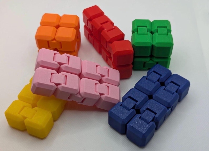 May include: A collection of colorful fidget toys in orange, red, green, pink, yellow, and blue. Each toy is composed of connected, interlocking blocks. The toys are designed to be manipulated and provide tactile sensory input.