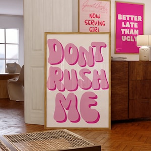 May include: Pink and white framed poster with the text "Don't Rush Me" in large, bubble-like letters.