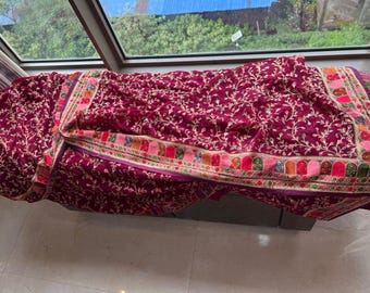 May include: A burgundy velvet shawl with a floral pattern and a colorful embroidered border.