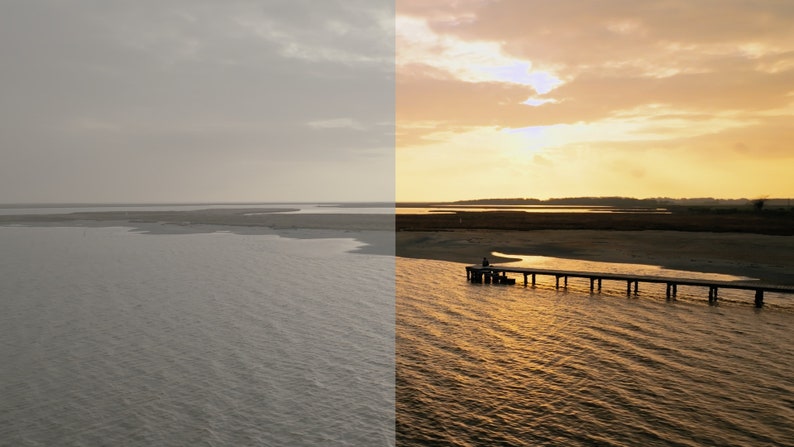 May include: A wooden pier extends out into a body of water with a person standing at the end. The water is calm and reflects the golden light of the setting sun. The sky is a soft orange and pink.