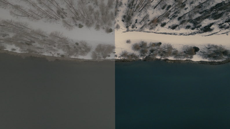 May include: An aerial view of a snowy forest with a path leading to a river. The river is a dark blue color and the forest is covered in white snow.