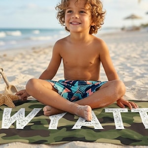 Child sitting on beach with camo name towel Wyatt, summer present boy bath wrap personalized name gift custom summer camp birthday favor pool party gift for little boy