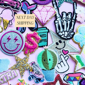 May include: A selection of vibrant embroidered patches on a pink backdrop. Patches feature a diamond, a smiley face with lightning bolts, a cactus, a roller skate, and a coffee cup that says "NEED COFFEE". The text "NEXT DAY SHIPPING" is also visible.