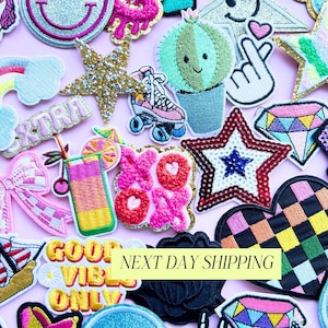 May include: A collection of colorful embroidered patches with various designs, including a smiley face, star, cactus, roller skate, and a cocktail. The patches are in various colors, including pink, gold, and green. The text "GOOD VIBES ONLY" is visible.