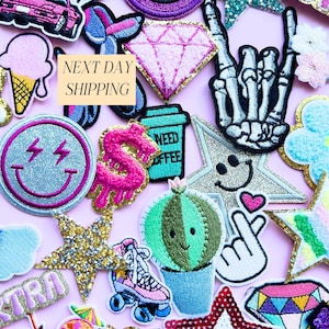 May include: A collection of colorful embroidered patches on a pink background. Patches include a diamond, a smiley face with lightning bolts, a cactus, a roller skate, a coffee cup, and a skeleton hand. The text "NEXT DAY SHIPPING" is also visible.