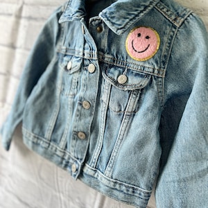 a denim jacket with a smiley face on it