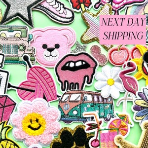 Puede incluir: Una colección de parches bordados en varias formas y colores, incluyendo un oso de peluche rosa, un jeep, una flor con una carita sonriente, un labio rosa, una margarita, un flamenco, un sol con gafas de sol y una furgoneta VW. El texto "NEXT DAY SHIPPING" también es visible.