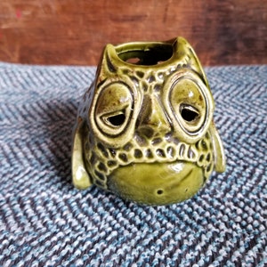 May include: A green ceramic owl planter with a textured surface and a hole in the top for planting.