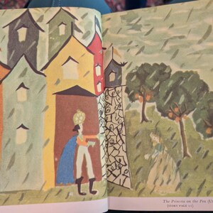 May include: Illustration from a children's book depicting a scene with colorful buildings, a figure in a blue cape, and a princess in a garden. The text reads "The Princess on the Pea (Uruguay, 8 years old) (STORY PAGE 11)".