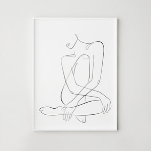 Puede incluir: Una impresión artística minimalista enmarcada. La obra presenta un dibujo de línea negra continua de una figura sentada con las piernas y los brazos cruzados. La figura está sobre un fondo blanco.