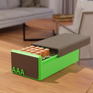 May include: A green and brown battery storage box with a lid open, revealing a compartment filled with AAA batteries. The box has the label "AAA" on the front.