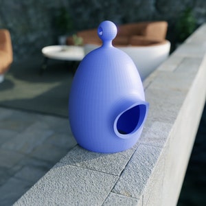 May include: A light blue, egg-shaped sculpture with a rounded top and a large, oval opening on the side. The sculpture is placed on a stone ledge, with a blurred background of a modern outdoor setting.