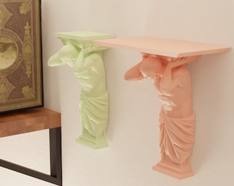 Peut inclure: Deux étagères murales au design unique. Chaque étagère est soutenue par une figure sculptée d'un homme tenant l'étagère avec ses bras. L'étagère de gauche est peinte en vert clair et l'étagère de droite est peinte en rose clair.