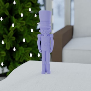 Puede incluir: Una figura de cascanueces de juguete de plástico morado. El cascanueces lleva un sombrero alto y tiene bigote.