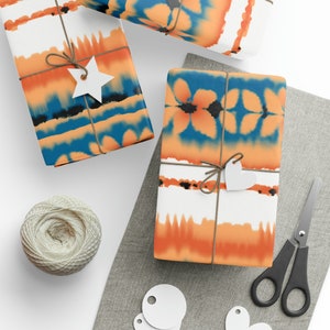 May include: Gift-wrapped presents with orange, blue, and white tie-dye patterned paper. Each package is tied with twine and a white tag. A ball of twine, scissors, and blank tags are also visible.