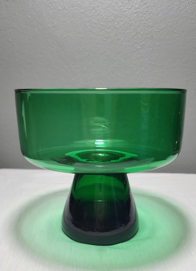 May include: A green glass pedestal bowl with a wide, round bowl and a flared, round base.