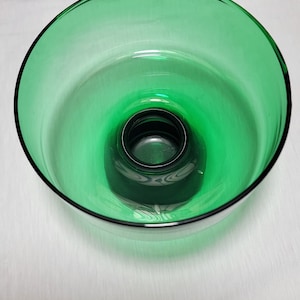 May include: A green glass bowl with a raised centre. The bowl is clear and has a slight green tint.