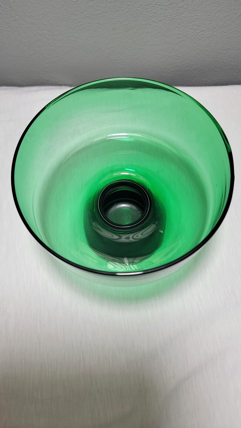 May include: A green glass bowl with a raised centre. The bowl is clear and has a slight green tint.