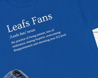Puede incluir: Una camiseta azul real con texto blanco que dice "Leafs Fans /Leafs fan/ sustantivo la práctica de ser paciente, prueba de resistencia, mantener la esperanza, superar la decepción y elevar tu coeficiente emocional"