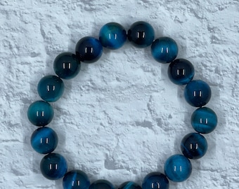 Puede incluir: Un brazalete de cuentas de ojo de tigre azul con cuentas redondas.
