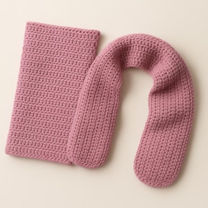 May include: A dusty rose-colored crochet neck wrap and rectangular pad. The neck wrap is U-shaped, designed to rest comfortably on the shoulders. The crochet stitch creates a textured surface. The pad is rectangular and made of the same material.