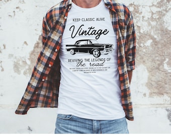 Könnte beinhalten: Weißes T-Shirt mit einer schwarzen Oldtimer-Grafik und den Worten "KEEP CLASSIC ALIVE Vintage REVIVING THE LEGENDS OF the road". Die Person trägt ein kariertes Hemd und blaue Jeans.