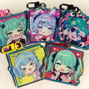 May include: A collection of five anime-style acrylic keychains. Each keychain features a colorful illustration of a character with large eyes and unique hairstyles. The keychains have metal clasps and colorful accents.