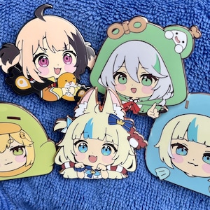 May include: Five colorful enamel pins featuring anime-style characters. The pins showcase various designs, including characters in frog and fox costumes. The pins have a glossy finish and are set against a blue background.