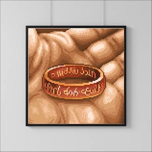 May include: A close-up of a hand holding the One Ring from The Lord of the Rings. The ring is made of gold and has the inscription "One Ring to rule them all, One Ring to find them, One Ring to bring them all and in the darkness bind them" in the Black Speech of Mordor.
